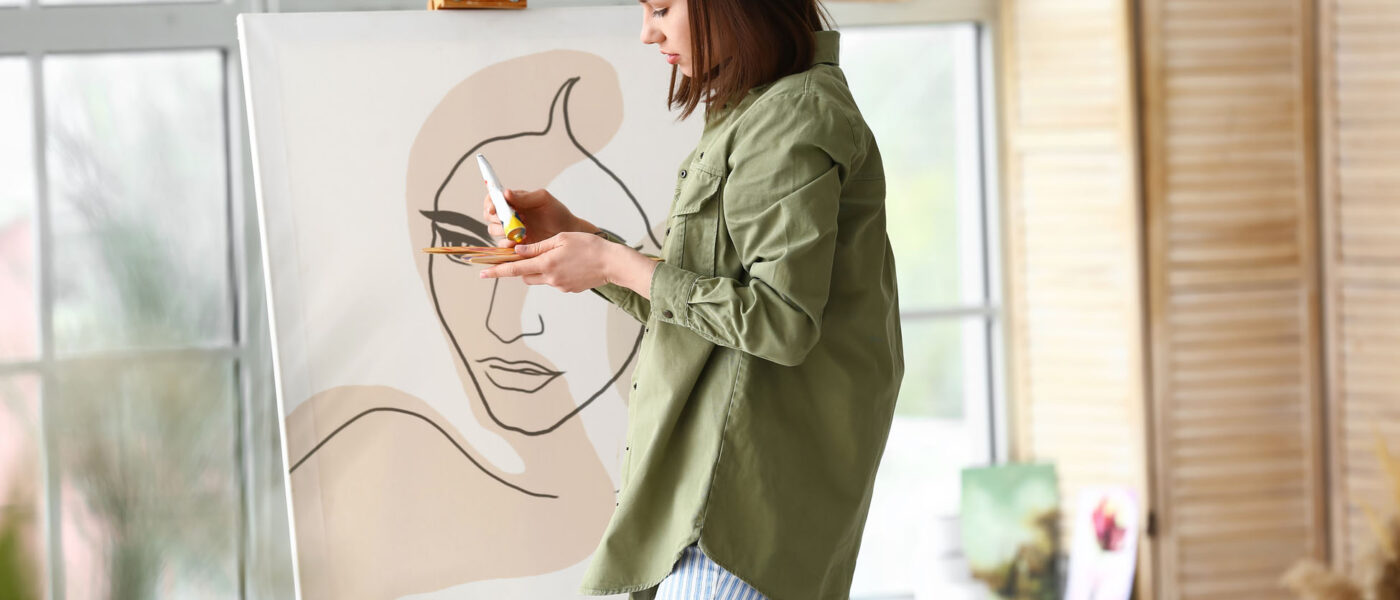 Young female artist painting in workshop Young female artist painting in workshop