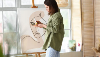Young female artist painting in workshop