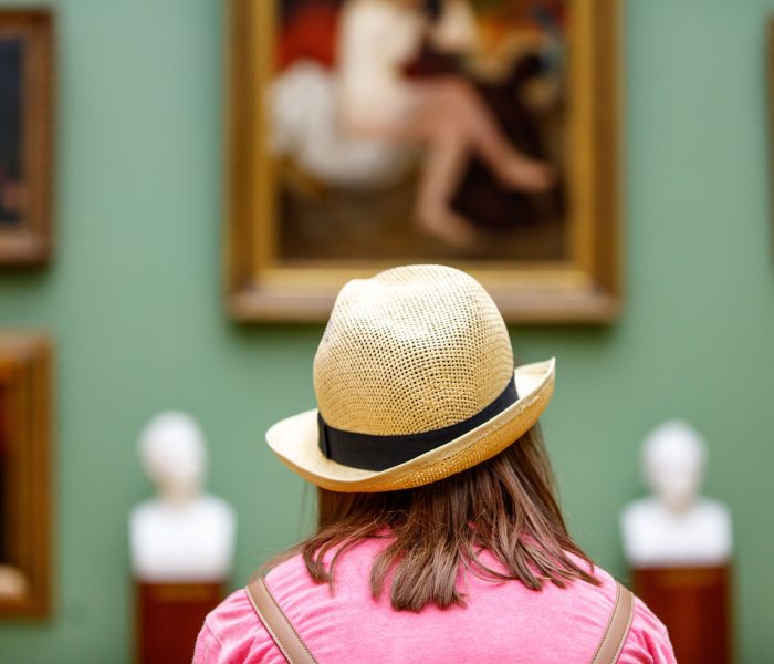Girl in a hat looks at paintings in a museum Girl in a hat looks at paintings in a museum